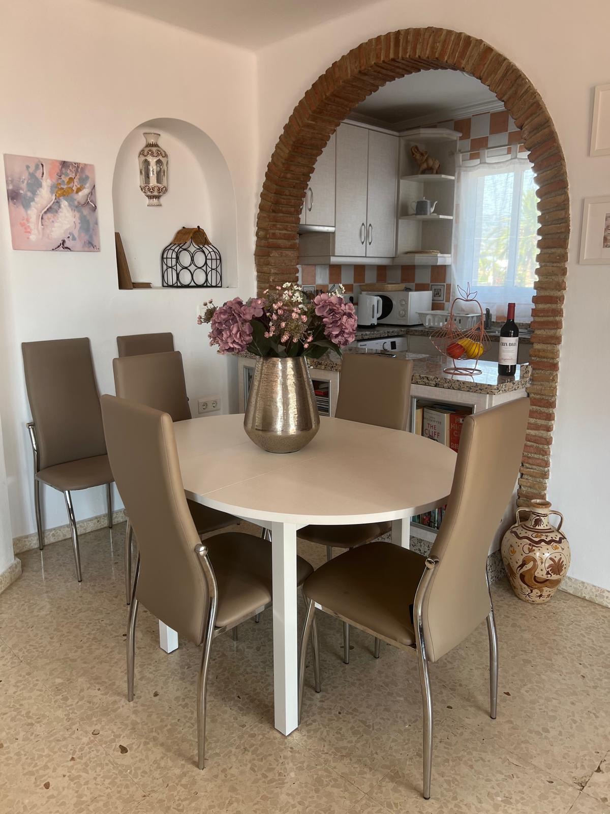 Dining table for six beneath the brick archway to the kitchen