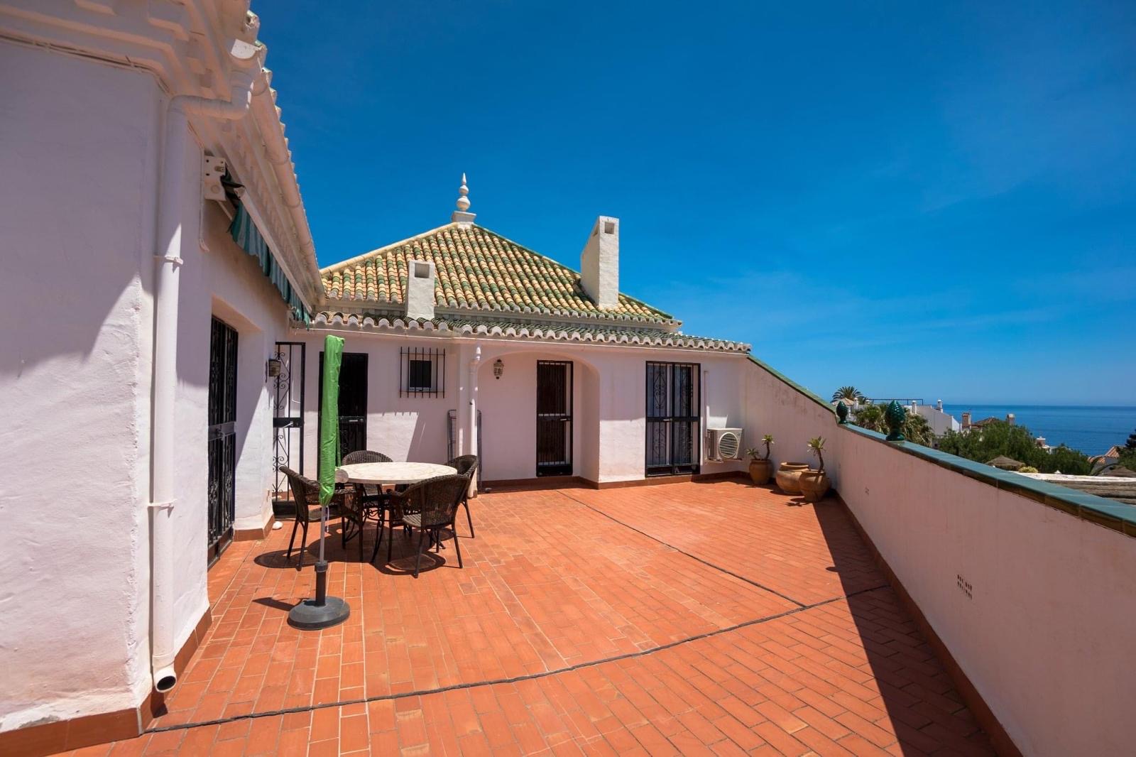 Terrace dining area with sea view beyond the wall