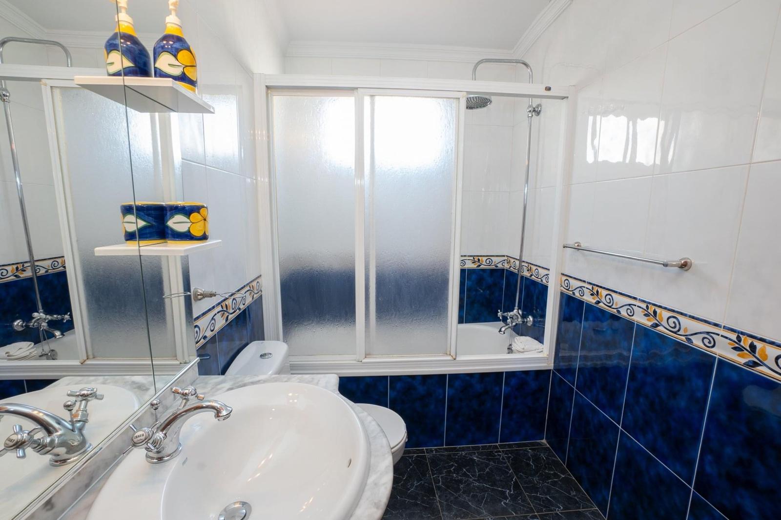 Bathroom with blue Andalusian tiles, bath and shower