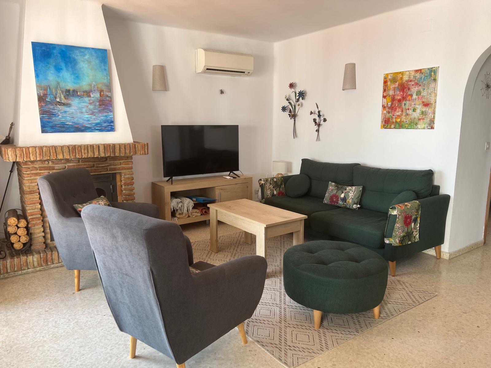 Living room with brick fireplace, green sofa and armchairs