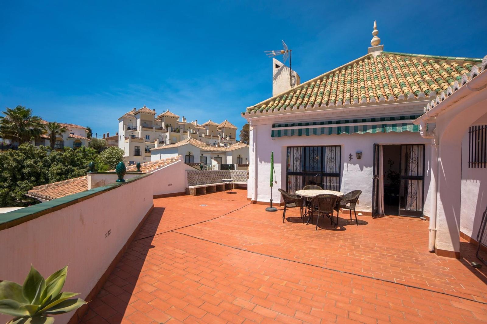 Spacious rooftop terrace with dining table, terracotta tiles and whitewashed buildings